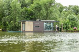 a small house on a boat on a body of water at Revolution Houseboat in Strijensas