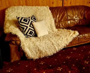 Un sofá de cuero marrón con dos almohadas. en Pensiunea Don Sergio, en Predeal