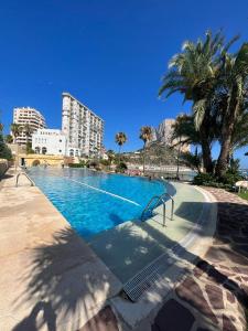 a large swimming pool with palm trees and a building at SOTAVENTO BEACH in Calpe