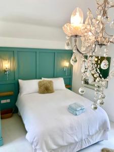 a bedroom with a white bed and a chandelier at The Coach House in Matlock
