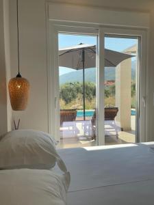 een slaapkamer met een bed en een patio met een parasol bij Casa O' - Moderne Villa mit großer Terrasse und privatem Swimmingpool in Skala Potamias