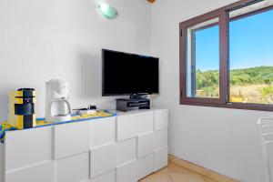 ein Wohnzimmer mit einem TV auf einem weißen Schrank in der Unterkunft Tenuta Villa Marianna - Almiddina in Telti