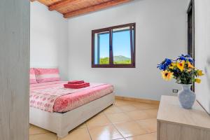 ein Schlafzimmer mit einem Bett und einer Vase mit Blumen in der Unterkunft Tenuta Villa Marianna - Almiddina in Telti