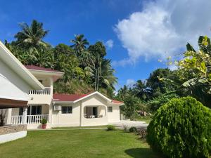 biały dom z ogródkiem i drzewami w obiekcie Paul's Residence w Mahé