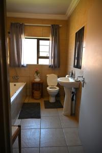 a bathroom with a toilet and a tub and a sink at Summersun Village in Parys