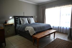 a bedroom with a bed with a bench and a window at Summersun Village in Parys