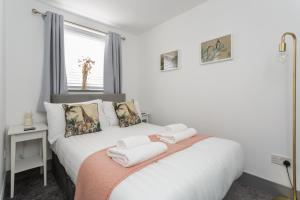 1 dormitorio con 1 cama con toallas en Wainscott Terrace - Spacious 2 double bedroom house with on-street parking short walk away from seafront, en Portsmouth