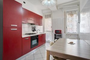 a kitchen with red cabinets and a wooden table at Easy Home vicino a Milano e Monza in Nova Milanese