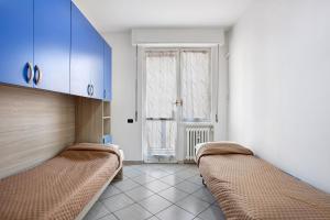 a room with two beds and blue cabinets and a window at Easy Home vicino a Milano e Monza in Nova Milanese