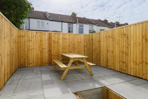 a wooden fence with a wooden picnic table on a patio at Wainscott Terrace - Spacious 2 double bedroom house with on-street parking short walk away from seafront in Portsmouth