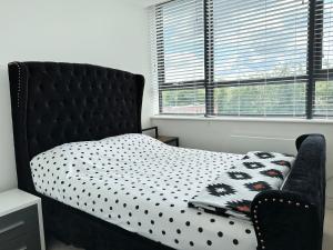 a bedroom with a bed with a polka dot bedspread and a chair at Cosy Apartment Haywards Heath in Haywards Heath