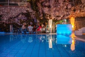 a swimming pool with people sitting at a restaurant at Villino rosso in Taormina +18 photos