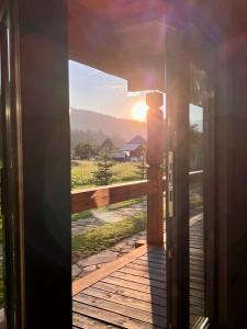 an open door to a balcony with the sun setting at Chalet PidStromom in Mykulychyn
