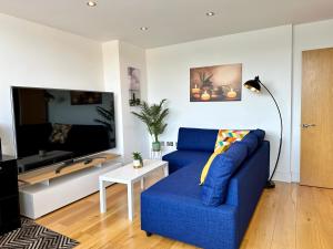 sala de estar con sofá azul y TV en Cosy Apartment Haywards Heath, en Haywards Heath