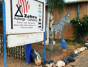 a sign with a zebra standing next to a building at Camping Auberge Zebra in Ouzoud