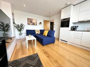 a living room with a blue couch and a kitchen at Cosy Apartment Haywards Heath in Haywards Heath