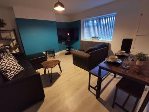 ein Wohnzimmer mit einem Sofa und einem Tisch in der Unterkunft Spacious 4 bed house, 7 Beds, Sofabed, Free Private Parking & Wifi in Birkenhead
