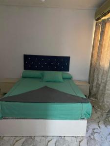 um quarto com uma cama com lençóis verdes e uma janela em North coast em Alexandria