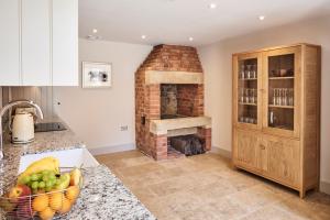 a kitchen with a brick fireplace and a basket of fruit at The Smithy in Hexham