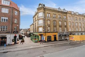 a city street with tall buildings and a bus at Lejlighed i hjertet af Aalborg in Aalborg