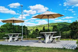 un grupo de mesas de picnic con sombrillas en Casa de Campo Warmup, en Caxias do Sul