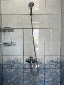 a shower with a hose on a tiled wall at MALIKA Guest House in Kochkorka