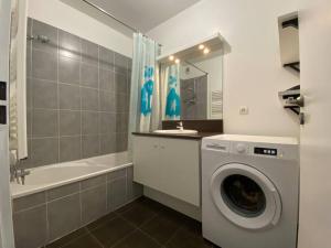 a bathroom with a washing machine and a bath tub at Très bel appartement cosy in Palavas-les-Flots