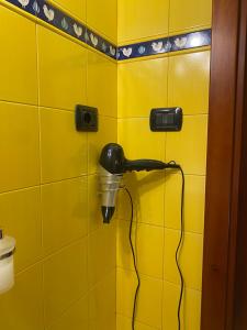 a yellow tiled bathroom with a blow dryer on a wall at Bed & Breakfast Casa Anna Rita in Vietri sul Mare