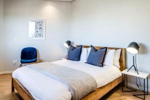 1 dormitorio con 1 cama grande con almohadas azules en Penthouse on S, en Ciudad del Cabo