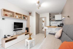 ein Wohnzimmer mit einem Sofa und einem Tisch sowie eine Küche in der Unterkunft Les Terrasses de Rangueil : studio avec parking in Toulouse