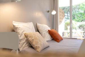 4 almohadas sentadas en una cama con ventana en Les Terrasses de Rangueil : studio avec parking, en Toulouse