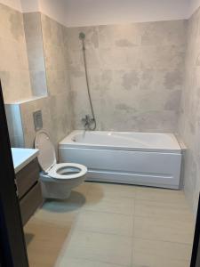 een badkamer met een bad, een toilet en een wastafel bij New Apartment Trivale Park in Piteşti