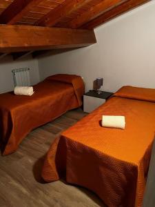 2 Betten in einem Zimmer mit orangefarbener Bettwäsche in der Unterkunft My Home - Mini appartamento in mansarda in Santa Venerina