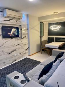 una habitación de hotel con TV en una pared de mármol en cobertura encantadora com jacuzzi, en Vila Velha