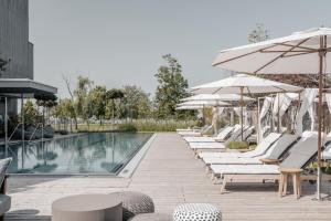 een rij ligstoelen en parasols naast een zwembad bij Nils am See in Weiden am See