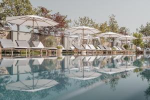 a swimming pool with umbrellas and chairs and water at Nils am See in Weiden am See