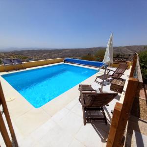 a swimming pool with chairs and an umbrella at La Colmena in El Puertecico