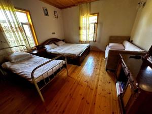 Habitación con 2 camas, suelo de madera y ventanas. en PARVIZ'S HOUSE, en Astara