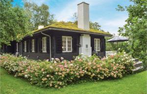 a small black house with flowers in front of it at Nice Home In Hornbk With 5 Bedrooms And Wifi in Hornbæk