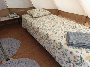 a bed in a tent with a blanket and pillows at Glamping Kotitila Kiveinen in Laitila