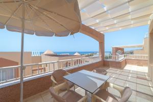 einen Balkon mit einem Tisch, Stühlen und einem Sonnenschirm in der Unterkunft Villas Monte Solana in Morro del Jable