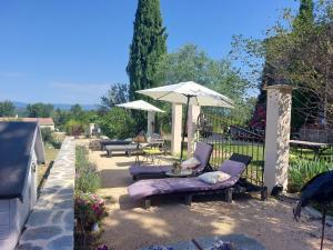 a patio with two chairs and an umbrella at La Flor Azul in Grospierres