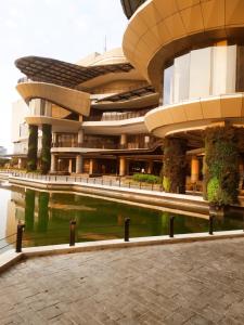 a building with a pool of water in front of it at DeAr Caspian Grand Sunkono Lagoon Apartment in Surabaya