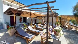 een groep stoelen en een parasol op een patio bij Styfilia Beachfront Apartment - Ground Floor in Sifnos