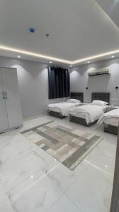 2 camas en una habitación con paredes blancas y suelo blanco en Manazel Al Faisal Furnished Apartments, en Al Bahah