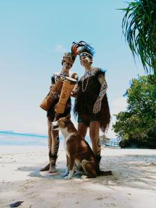 a couple of people and a dog on the beach at Raja Ampat Sandy Guest House in Saonek