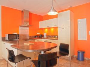 - une cuisine aux murs orange avec une table et des chaises dans l'établissement Appartement Le Palais, 2 pièces, 3 personnes - FR-1-418-95, au Palais