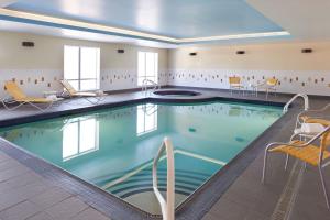 einen Pool in einem Hotelzimmer mit Stühlen und einem Pool in der Unterkunft Fairfield Inn & Suites by Marriott Barrie in Barrie