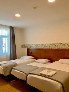 a room with three beds and a window at Hotel Vila Verde in Castro Verde