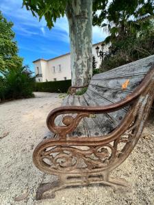 un viejo banco de madera sentado junto a un árbol en Chateau de la Clapiere en Hyères